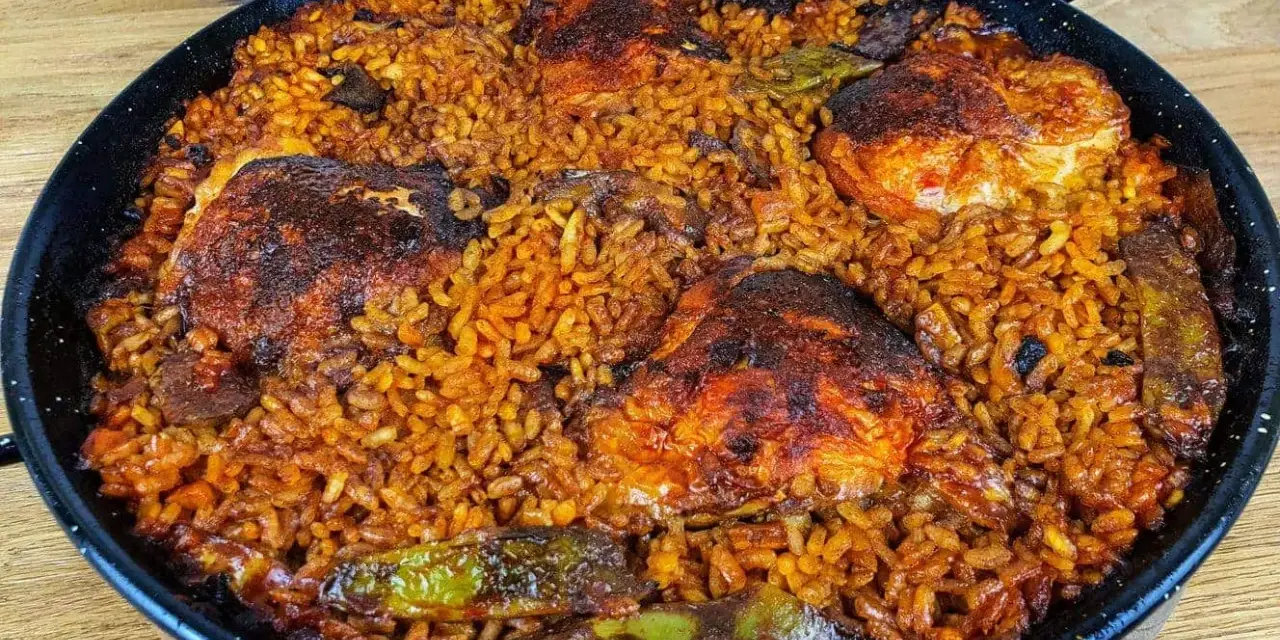 Pyszna paella z kurczakiem, ryżem i warzywami w tradycyjnej patelni.