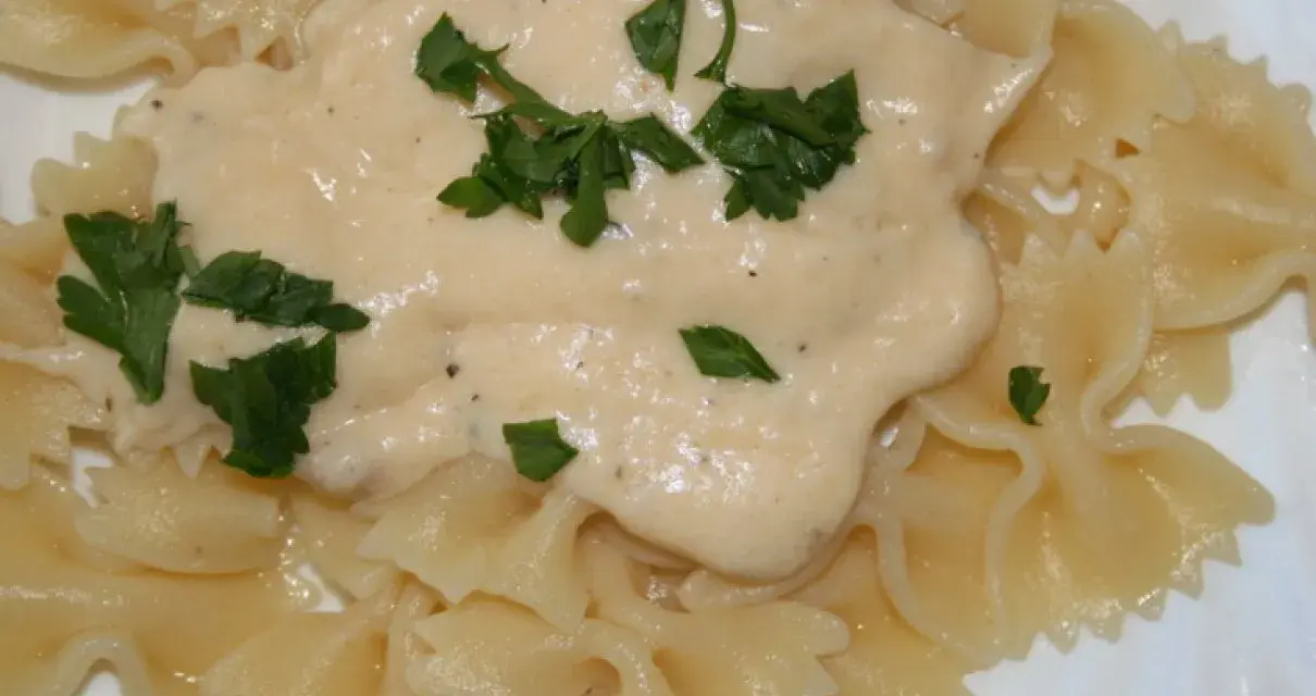 Pyszny sos serowy do makaronu farfalle, udekorowany świeżą natką pietruszki. Idealny na szybki obiad.