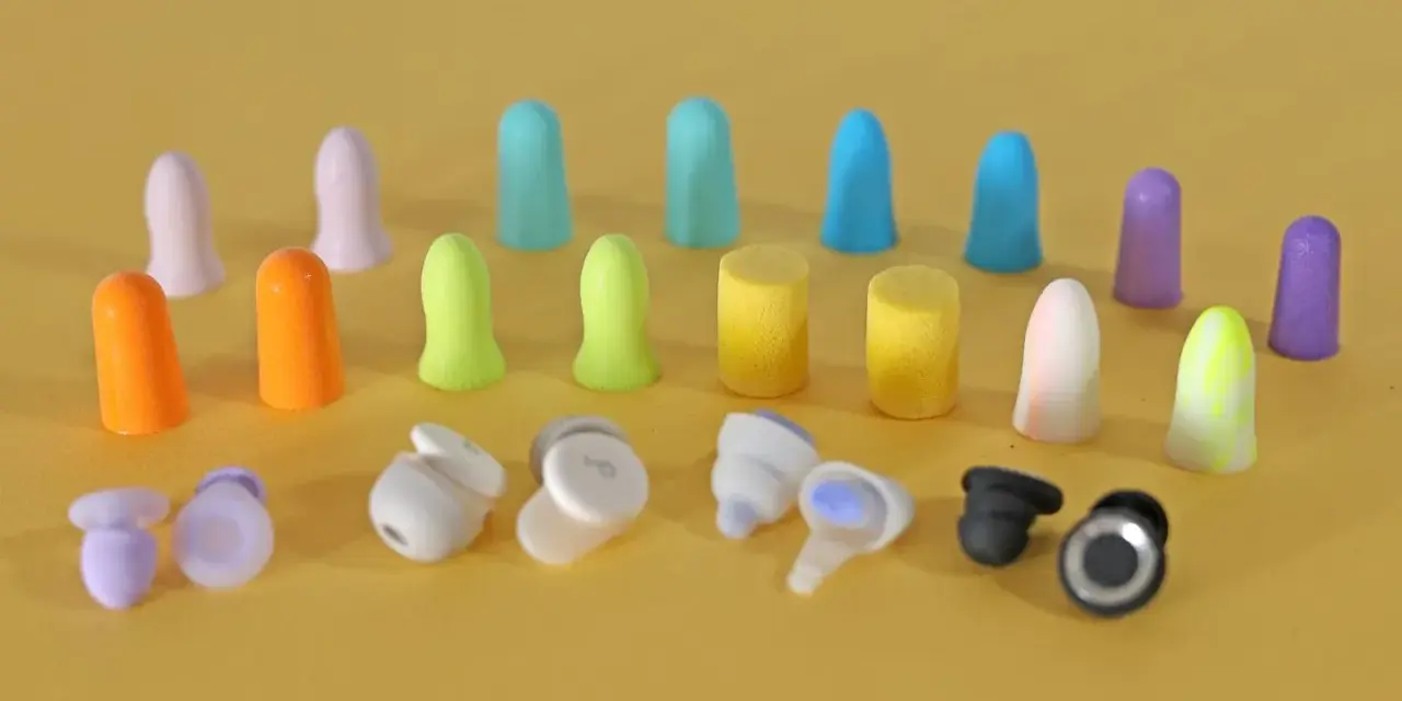 Apprenez comment mettre des bouchons d'oreilles en mousse. Divers bouchons colorés et écouteurs sans fil sont disposés sur fond jaune.