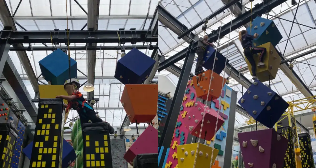 Kinder klettern auf bunte Würfel und Wolkenkratzer in einer Kletterhalle, die an einen Magic Mountain Berlin erinnert.