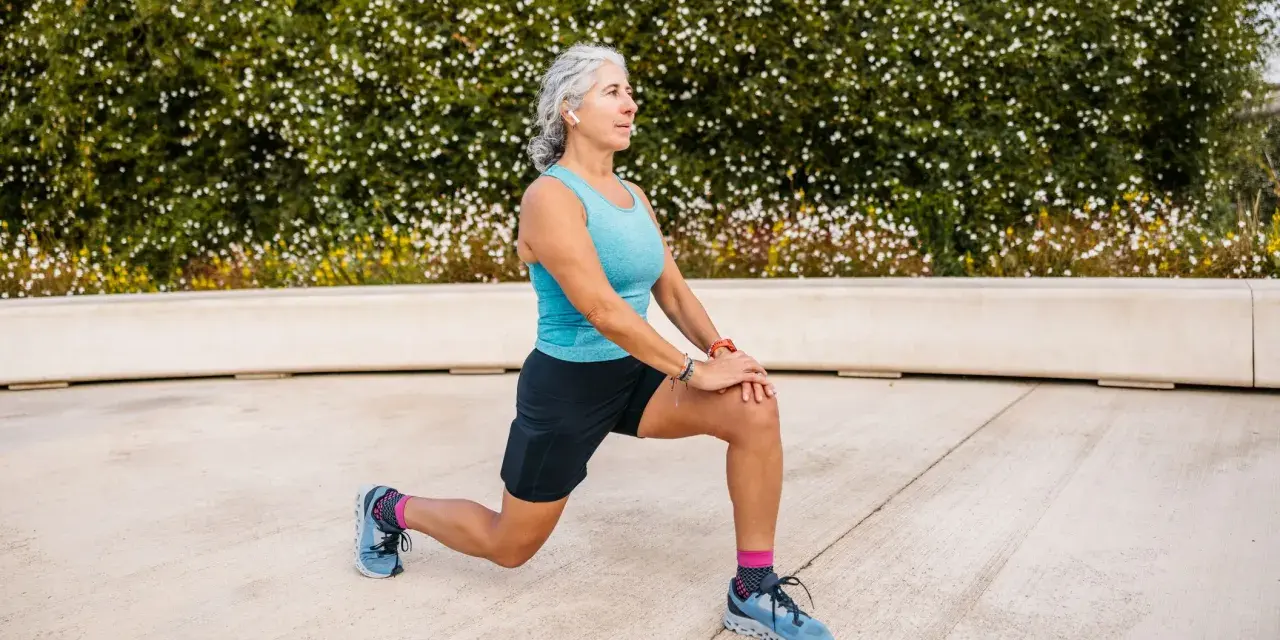 Femme âgée faisant un étirement des jambes, préparation pour un échauffement pieds randonnée.