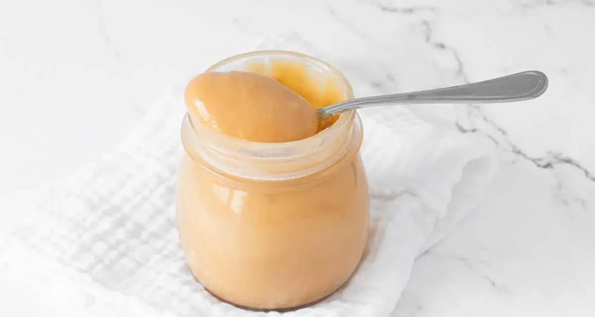 Un tarro de manjar blanco cremoso, listo para ser disfrutado con una cuchara.