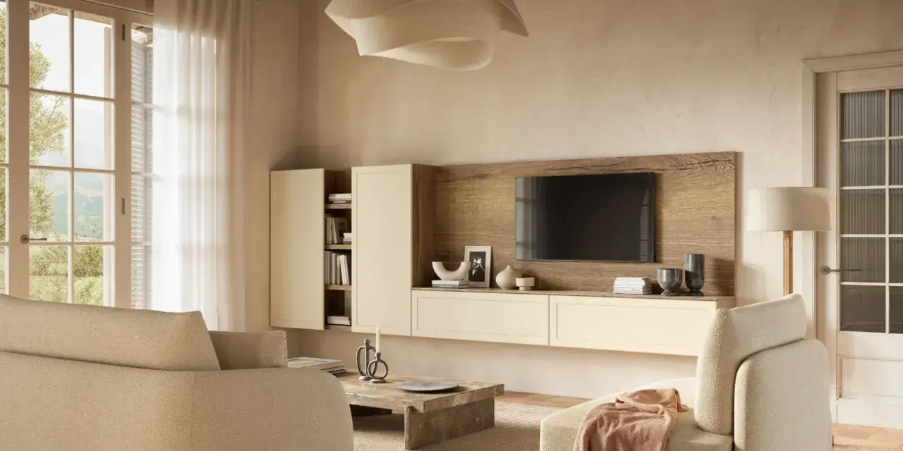 Soggiorno accogliente con divani color visone abbinamento, mobile TV in legno e pareti color crema. Luce naturale entra da un'ampia finestra.