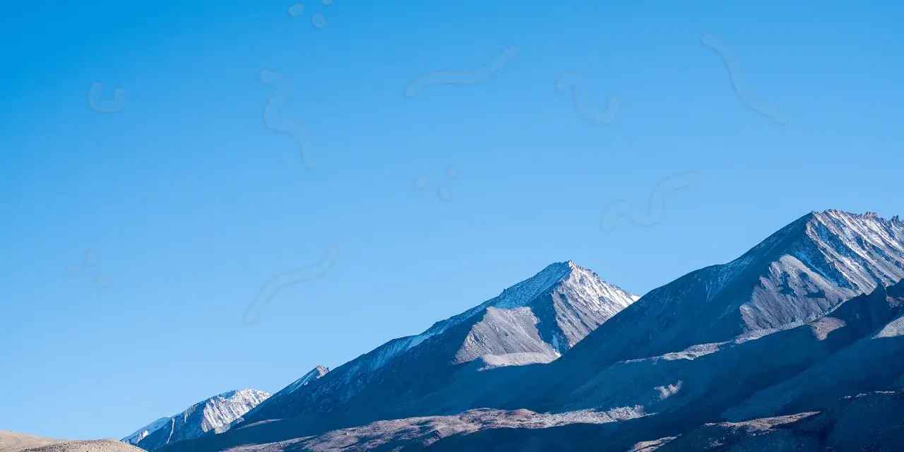 Sullo sfondo di montagne innevate, un cielo azzurro limpido è punteggiato da forme sinchisi scintillante, come piccoli puntini e curve sinuose.