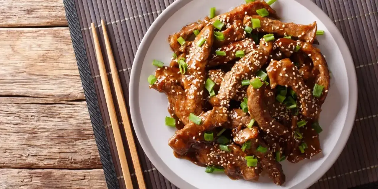 Pyszny kurczak teriyaki z sezamem i szczypiorkiem, gotowy do jedzenia pałeczkami.