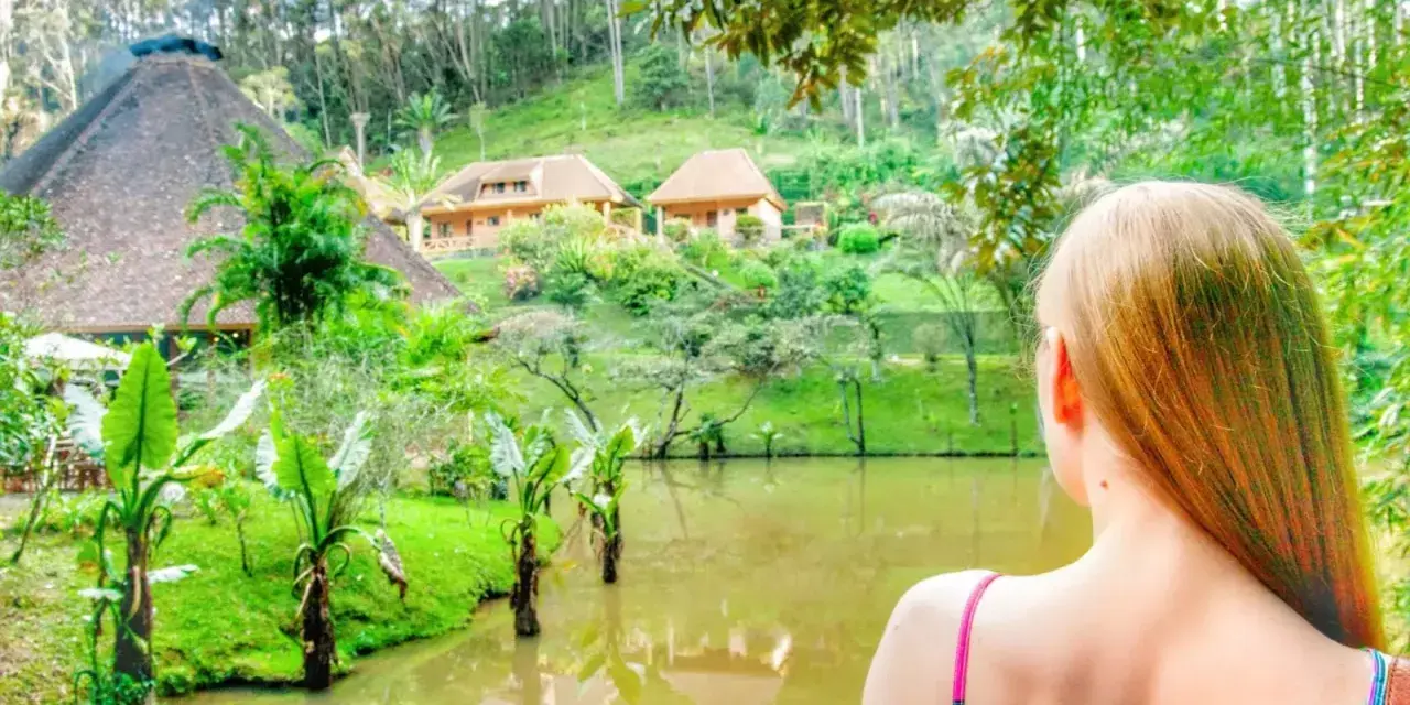 Widok na malowniczy krajobraz z jeziorem i domkami w stylu madagaskarskim. Atrakcje przyrodnicze i architektoniczne zachwycają.