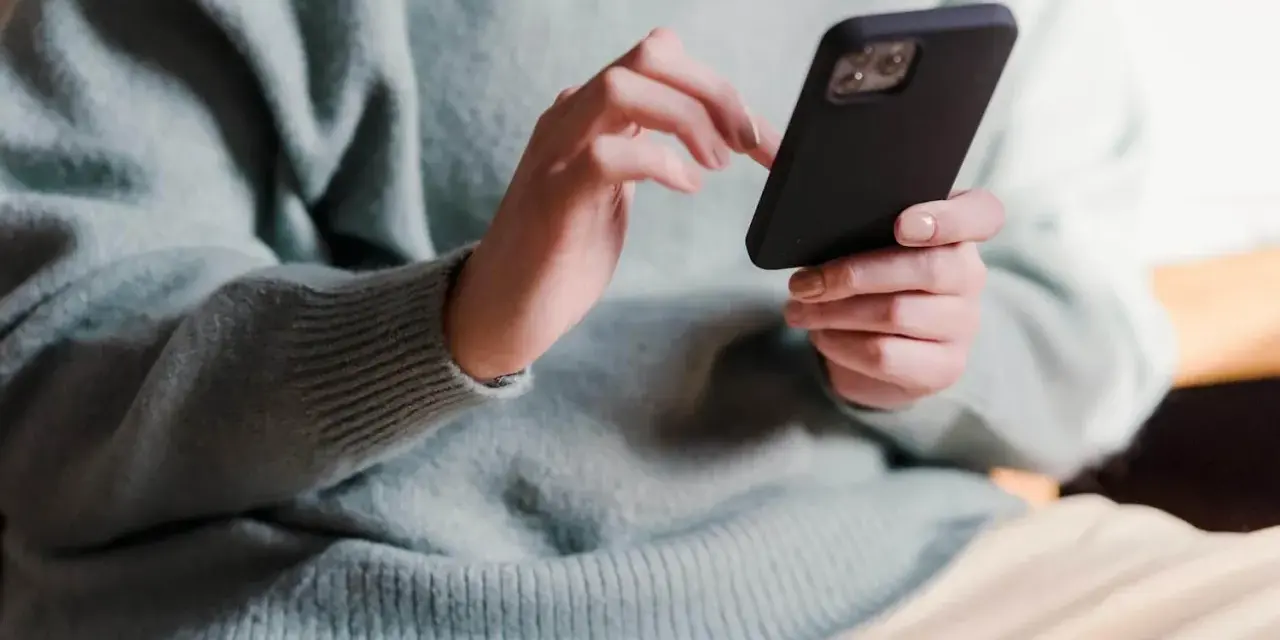 Dłonie trzymające telefon, zastanawiające się, co napisać po kłótni.
