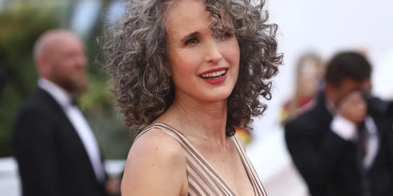 Mujer sonríe con modernos cortes de pelo con canas, luciendo un vestido a rayas.