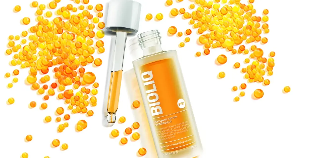 BiolIQ intensywne serum rewitalizujące w buteleczce z pipetą, otoczone kropelkami o pomarańczowym odcieniu.