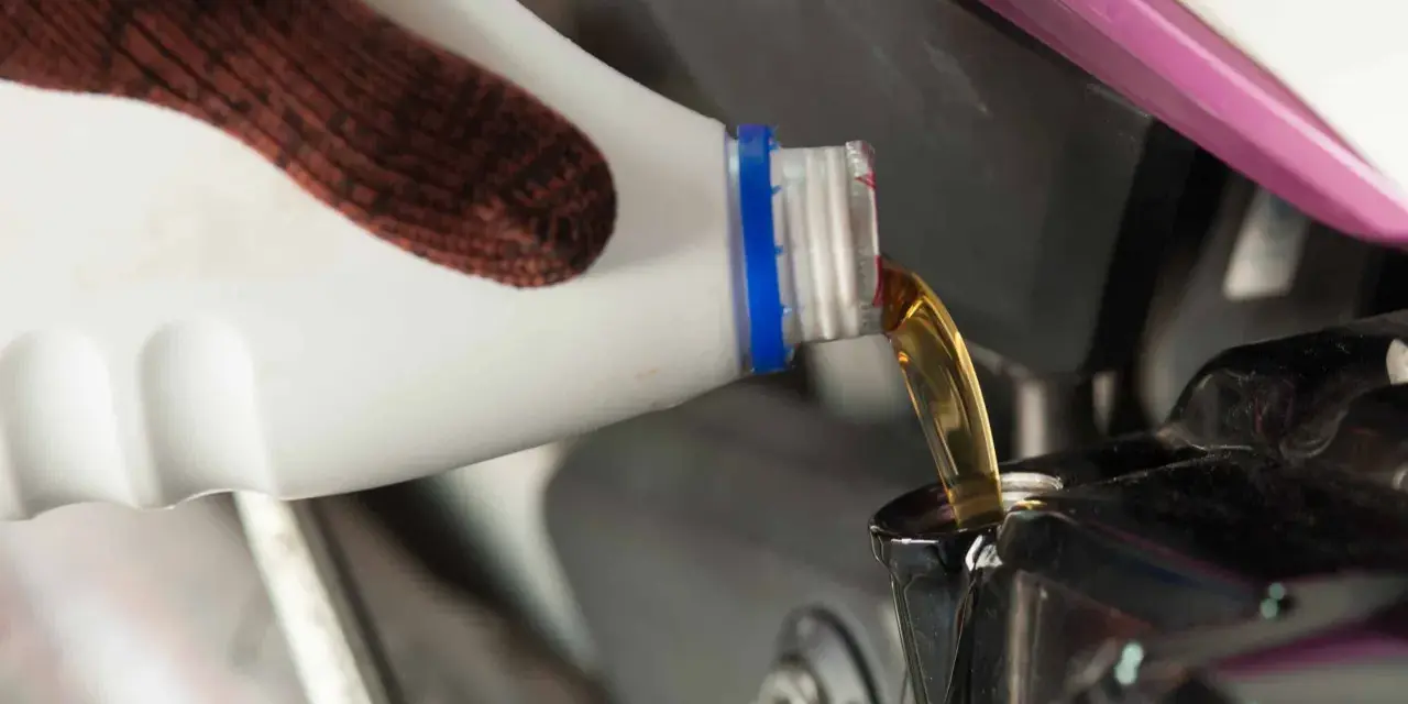 Rękawica nalewa nowy olej do silnika motocykla podczas wymiany oleju.