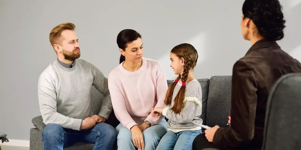 Rodzina z córką siedzi na kanapie podczas sesji z psychologiem.