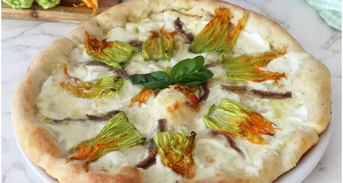 Pizza con fiori di zucca, mozzarella filante e acciughe. Un sapore delicato e profumato, perfetto per l'estate.