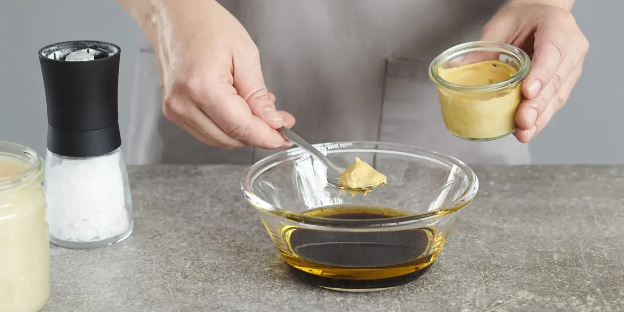 Senf wird zu einer Schüssel mit Öl und Balsamico-Dressing gegeben.