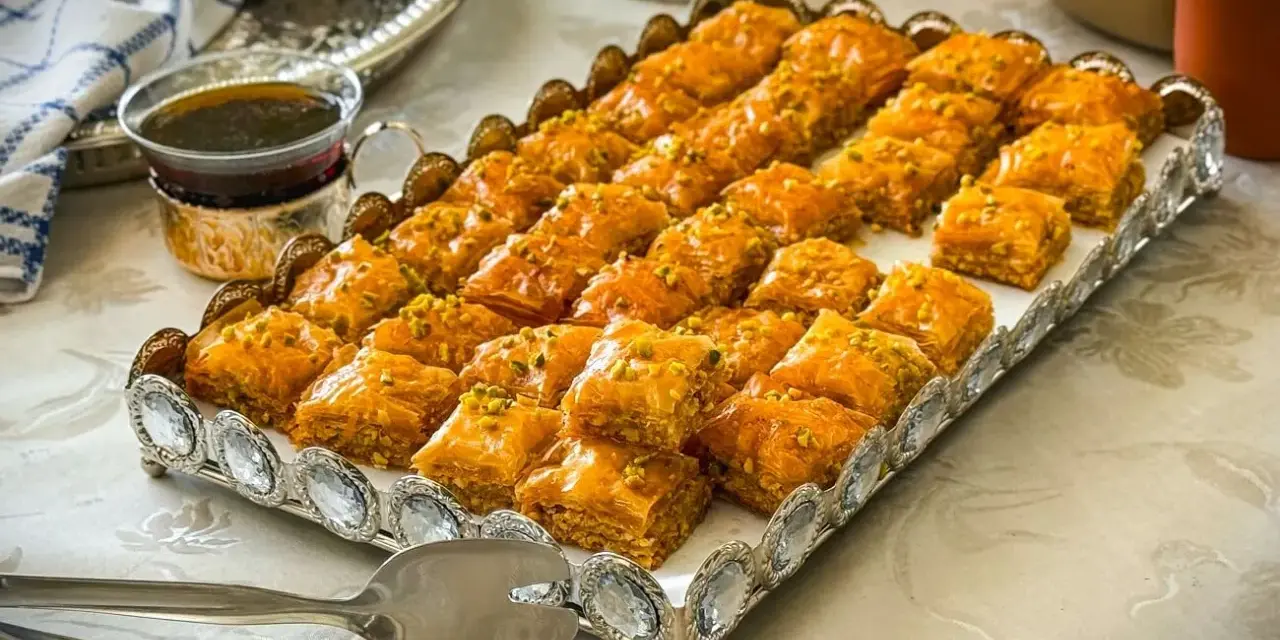Ein Tablett voller goldbrauner Baklava, bestreut mit Pistazien. Dieses köstliche Baklava-Rezept ist perfekt für jede Feier.
