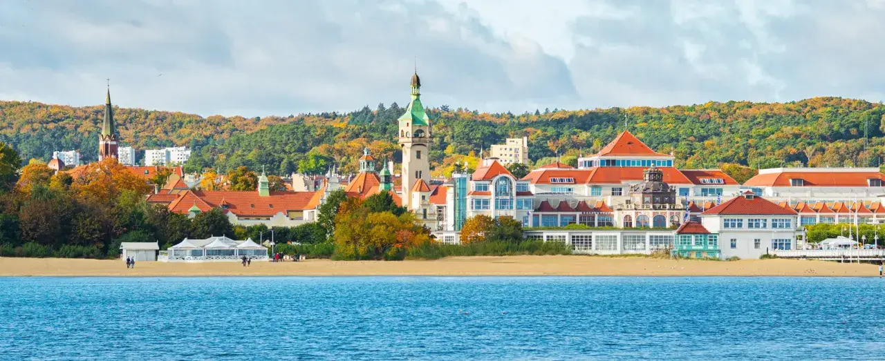 Malownicze budynki i plaża w Sopocie, idealne miejsce, by zobaczyć w Sopocie. W tle jesienne drzewa.