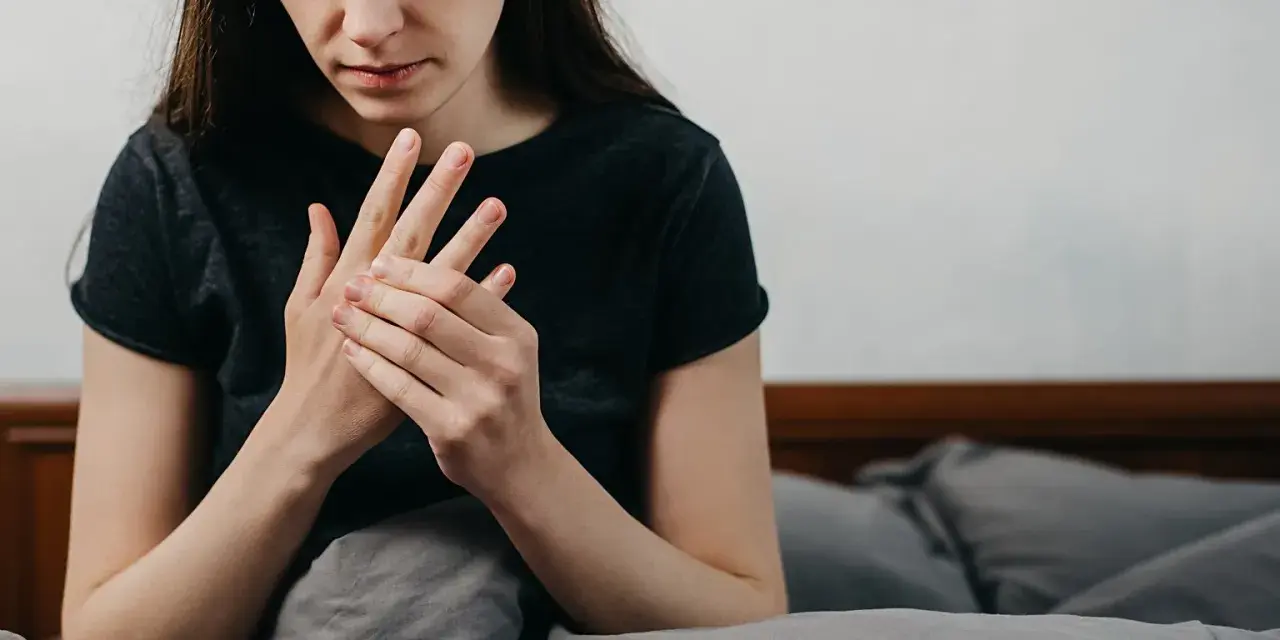 Kobieta masuje dłoń, odczuwając drętwienie rąk w nocy.