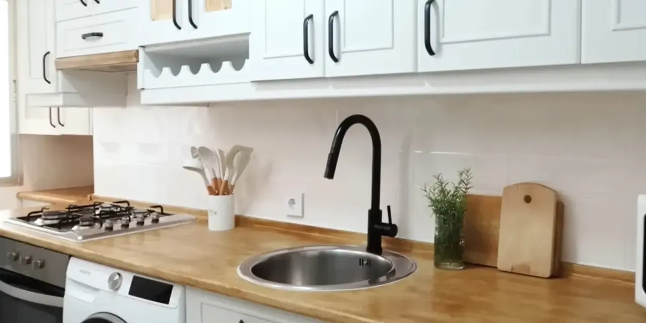 Cocina renovada: gabinetes blancos, encimera de madera y grifo negro. ¡Un ejemplo de cómo pintar muebles de melamina para darles nueva vida!