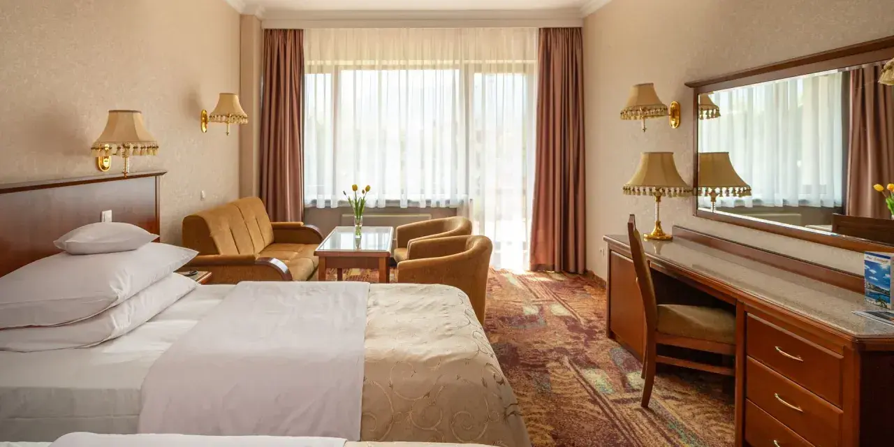 Pokój w hotelu Gołębiowski Wisła: dwa łóżka, kanapa, fotele, biurko i lustro.