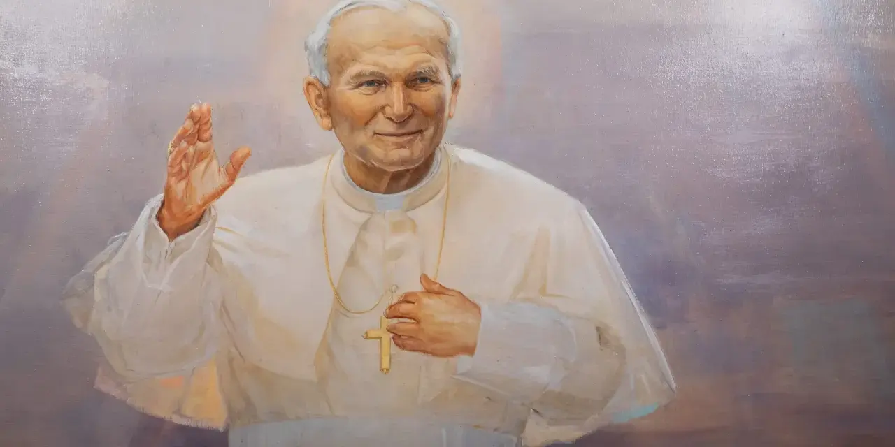 Obraz przedstawia Jana Pawła II w białej szacie, z podniesioną prawą dłonią i krzyżem na piersi. Wierni odmawiają modlitwę do Jana Pawła II o uzdrowienie.