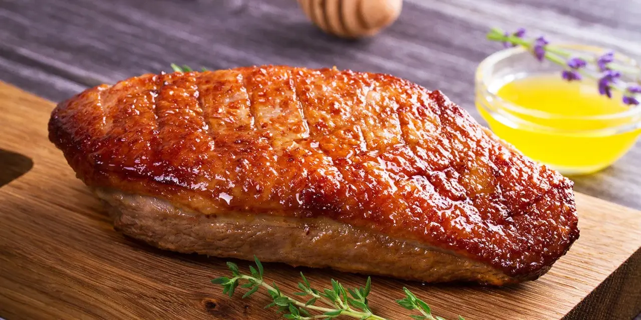 Un magret de canard au barbecue, la peau dorée et croustillante, prêt à être dégusté avec une touche de miel et de thym.