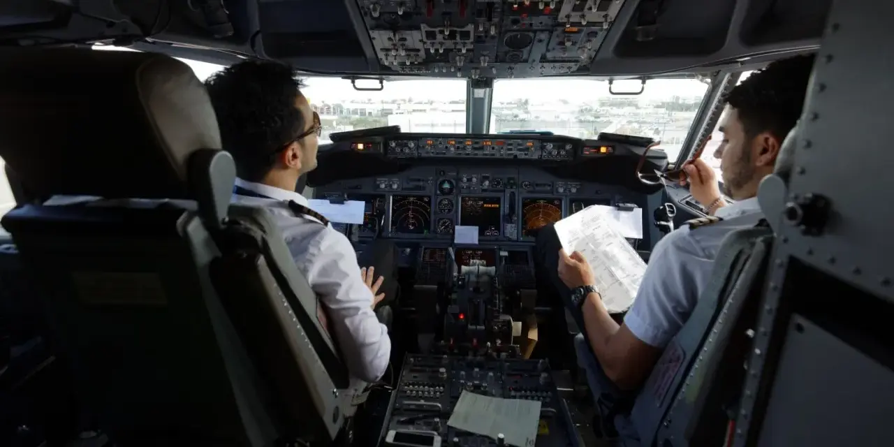 Dwóch pilotów w kokpicie samolotu, dyskutujących o trasie. Ciekawe, ile zarabia pilot Ryanair?
