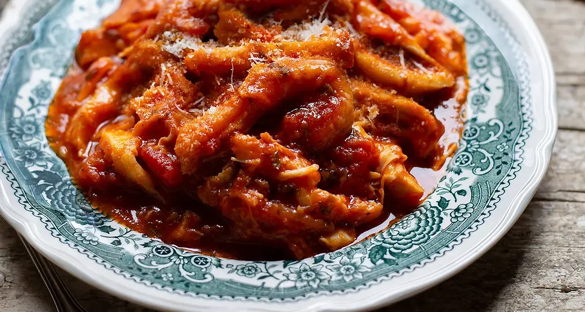 Un piatto fumante di trippa alla romana, ricca e saporita, servita su un piatto decorato.