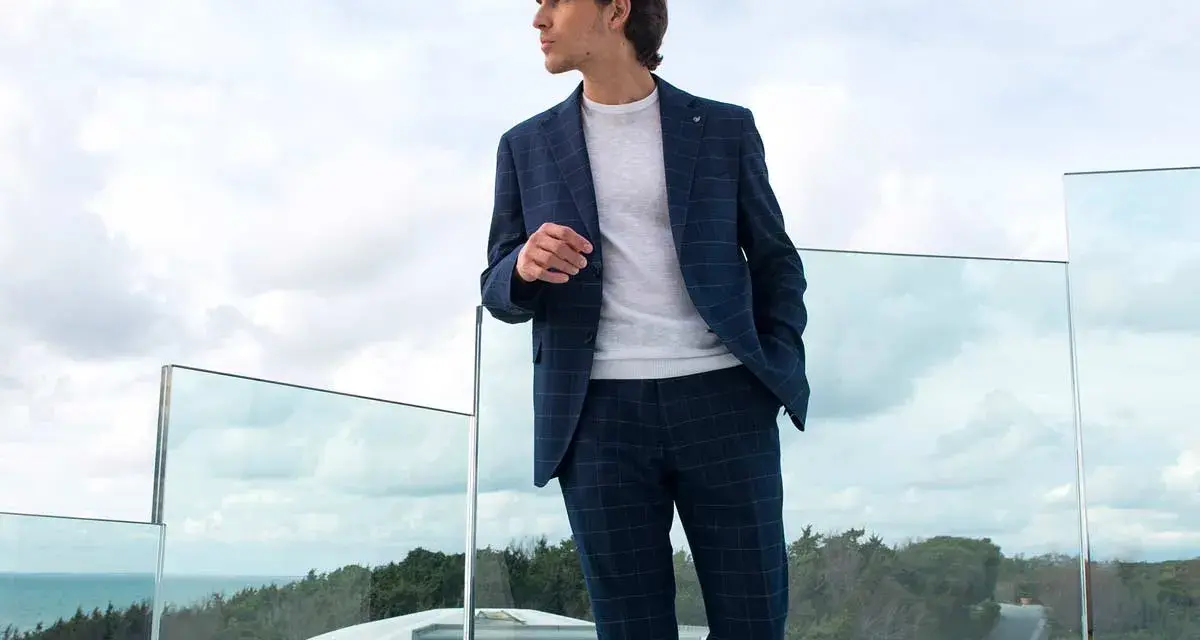 Uomo con tailleur blu a quadri, maglione bianco. Perfetto per capire con che scarpe abbinare.