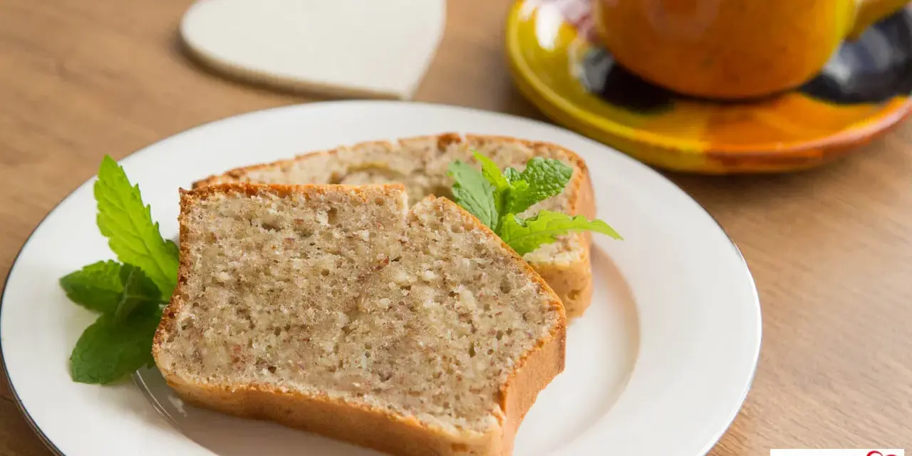 Zwei Scheiben saftiger Becherkuchen mit Joghurt, garniert mit Minze, neben einer Tasse Kaffee.