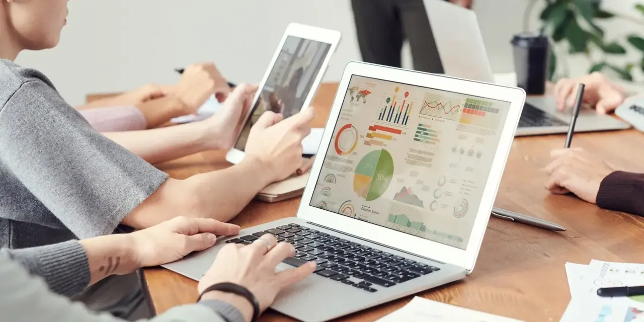 Analityk finansowy pracuje nad raportem na laptopie, analizując wykresy i dane.