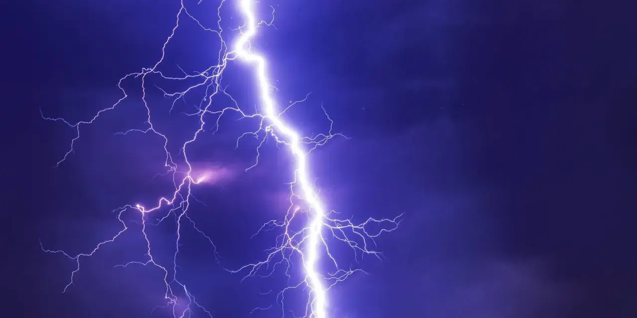 Potężne wyładowanie atmosferyczne rozświetla nocne niebo. Burza może oznaczać problemy, ale pamiętaj o możliwości uzyskania odszkodowanie za brak prądu.