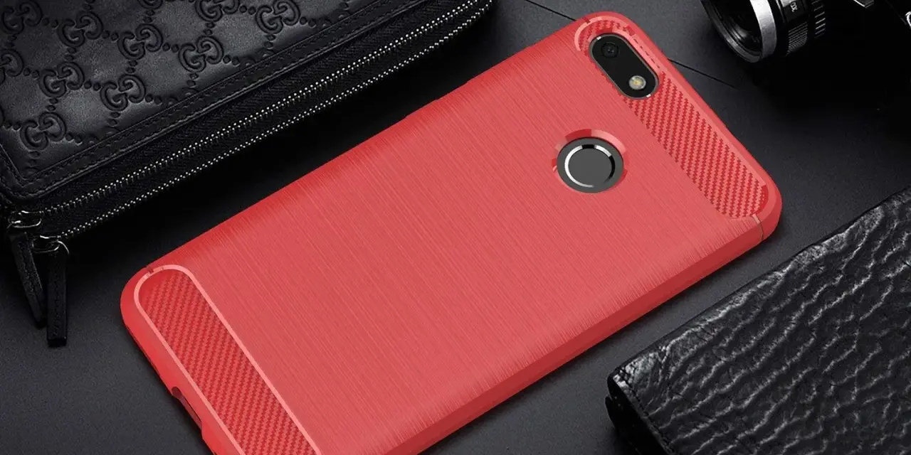 Czerwone etui na telefon Huawei Y6 Pro (2017) z karbonowymi wstawkami, obok czarnego portfela i aparatu.
