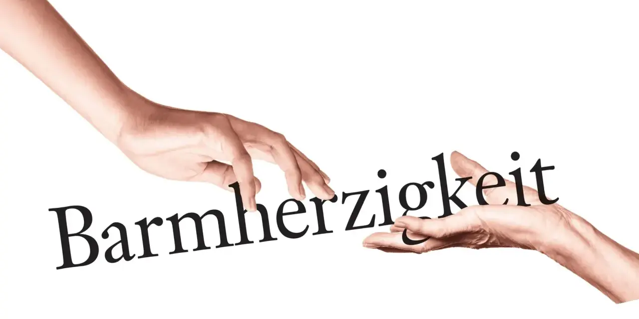 Zwei Hände berühren das Wort "Barmherzigkeit". Eine Hand reicht es der anderen, ein Symbol für die Werke der Barmherzigkeit.