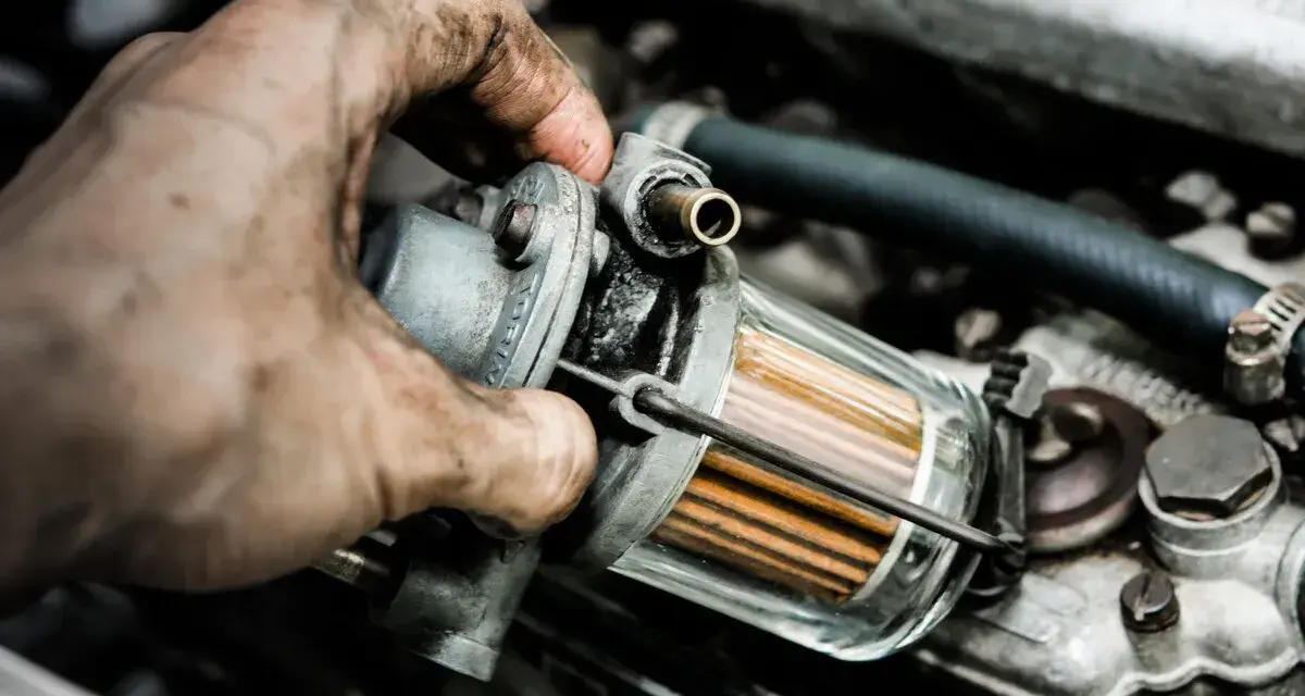 Brudna ręka mechanika trzyma filtr paliwa. Zapchany filtr gazu objawy mogą być różne, np. nierówna praca silnika.