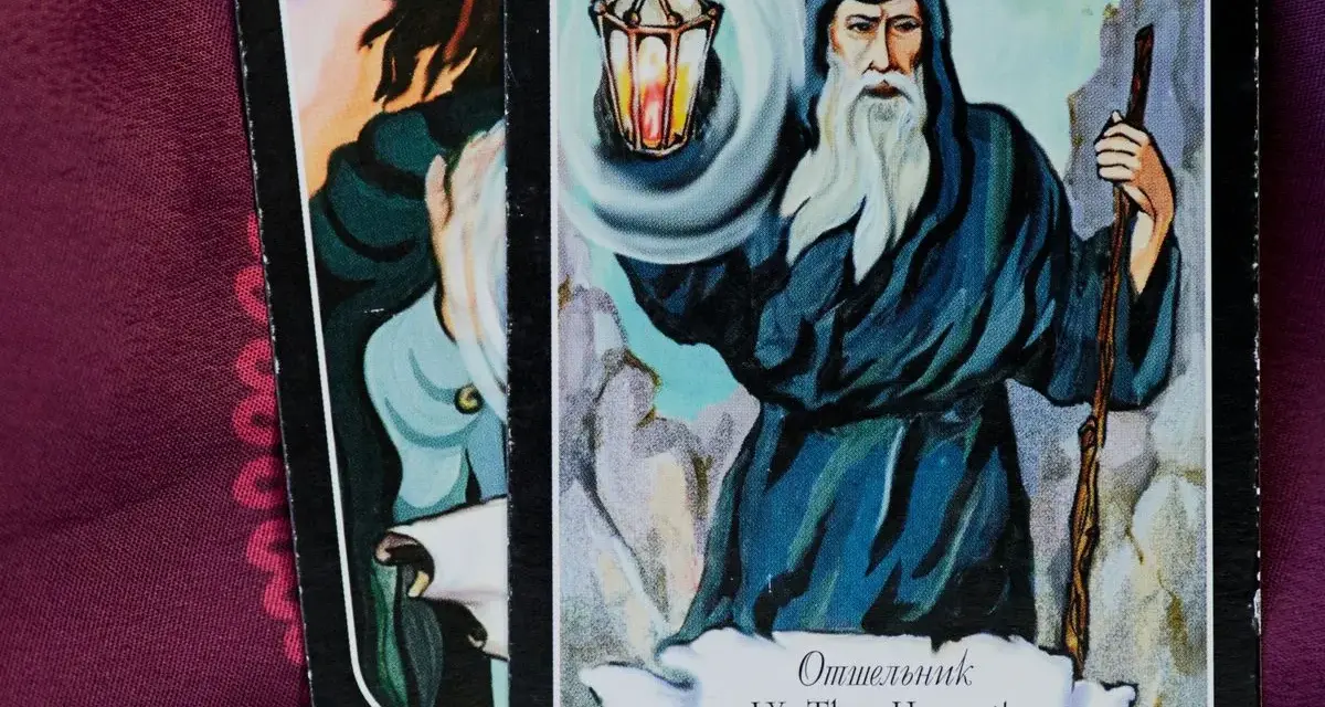 El tarot del mundo ermitaño: un sabio anciano con barba blanca ilumina el camino con una linterna, guiando en la introspección.