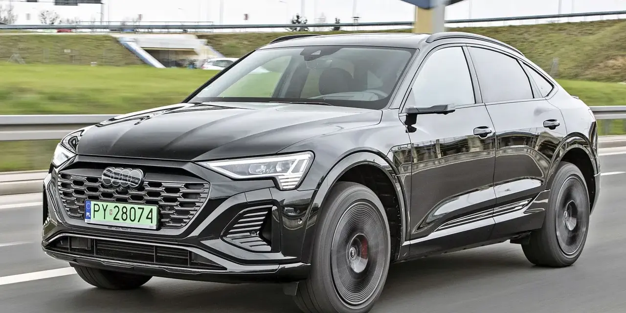 Czarny Audi Q8 e-tron sunie po drodze. Zastanawiasz się nad audi q8 cena? Ten luksusowy SUV coupe robi wrażenie.