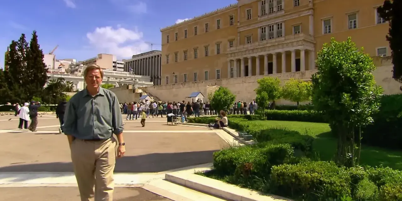Rick Steves explores Athens, standing before the Hellenic Parliament building with a crowd gathered for the changing of the guard.