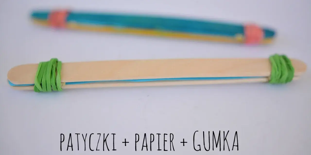 Proste instrumenty muzyczne do zrobienia: patyczki, papier i gumka. Dwa patyczki połączone gumkami, jeden z kolorowym papierem w środku.