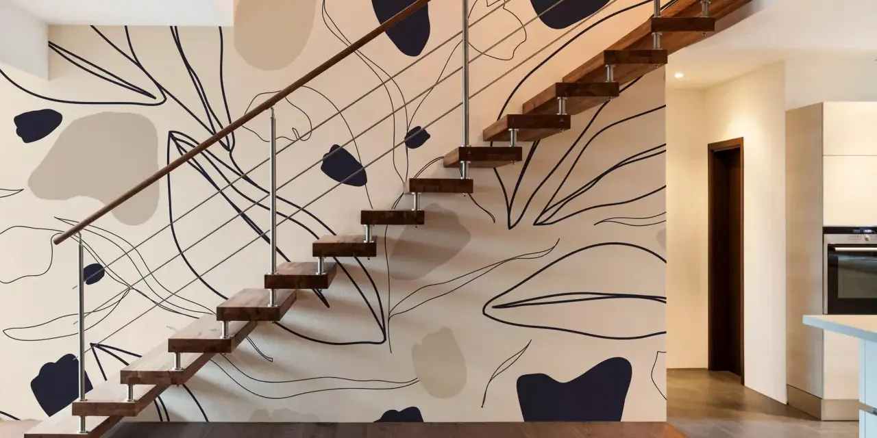 El papel pintado en las paredes de esta casa moderna presenta un diseño abstracto de hojas y formas orgánicas en tonos tierra, complementando la escalera flotante de madera.