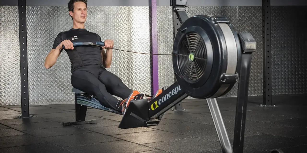 Un homme en tenue de sport effectue un exercice rameur dans une salle de sport.