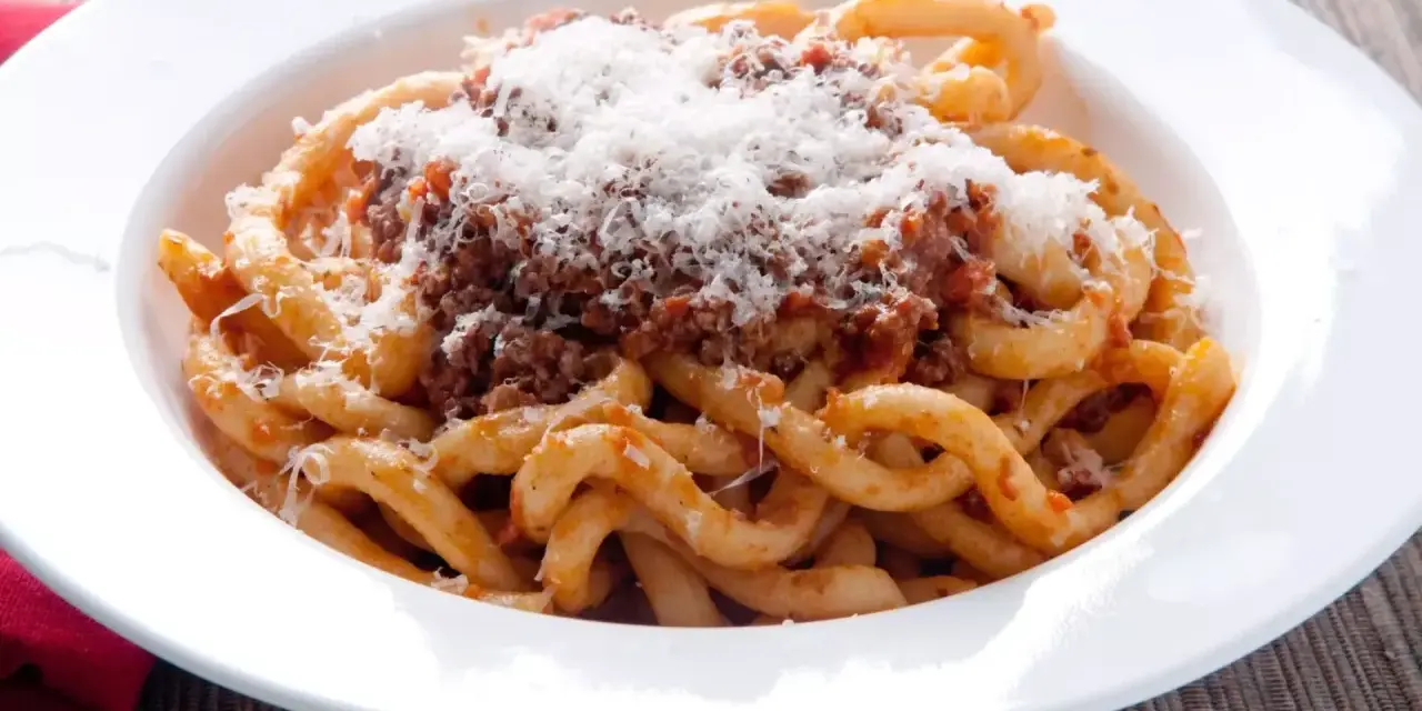 Pici al ragù, un classico da provare per scoprire cosa mangiare a Siena. Pasta fatta a mano con sugo di carne e abbondante pecorino.