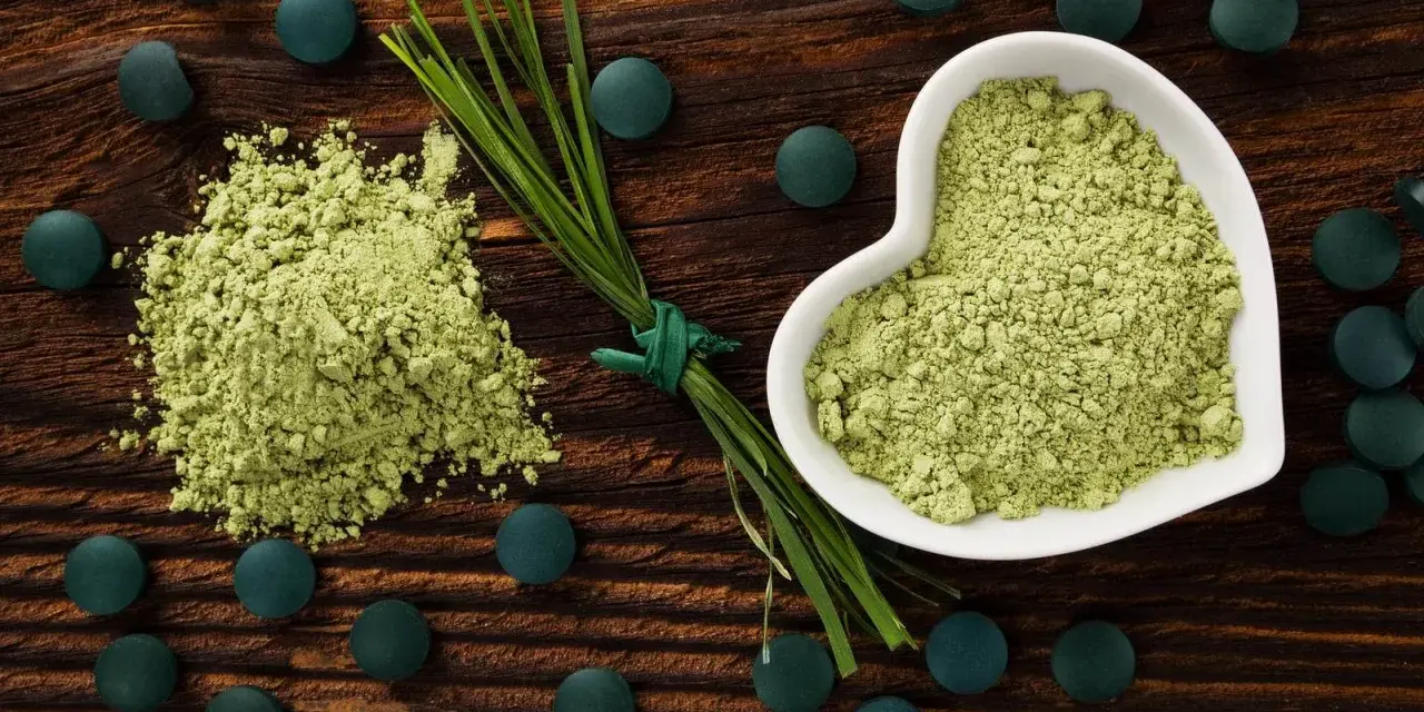 Zielony proszek i tabletki na drewnianym tle. Dowiedz się, spirulina co to za superfood!