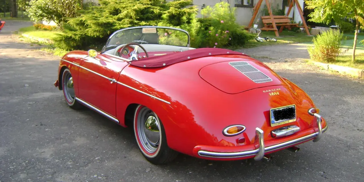 Czerwony kabriolet Porsche 356 z lat 50. stoi na podjeździe, gotowy na letnią przejażdżkę.