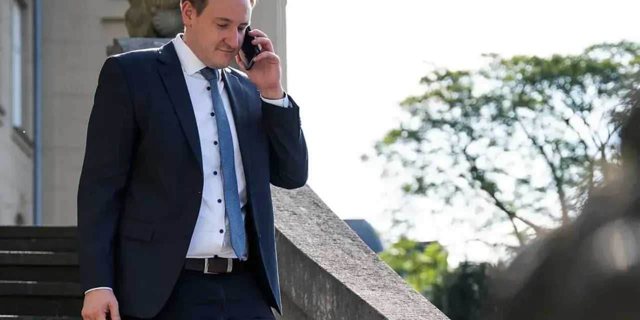 Anwalt am Telefon, der überlegt, wie kann ich mich schnell scheiden lassen. Er trägt einen dunklen Anzug und hält eine Aktentasche.