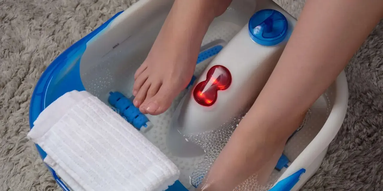 Pieds dans un bain à bulles, profitant d'un moment de détente pour la beauté des pieds. Une serviette blanche est à portée de main.