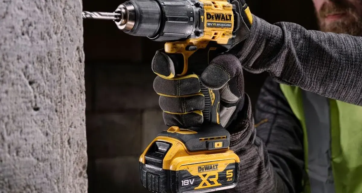 Mężczyzna w rękawicach wierci w betonie najmocniejszą wkrętarką DeWalt 18V XR.
