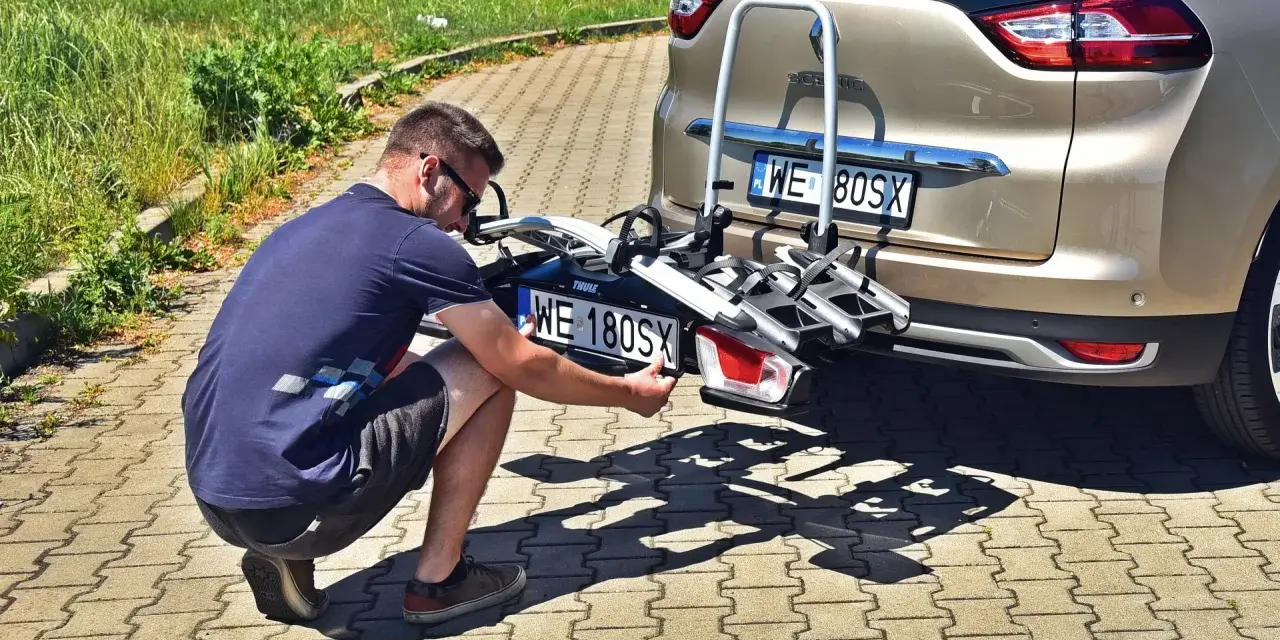 Mężczyzna montuje tablicę rejestracyjną na bagażniku rowerowym, by uniknąć mandatu za brak tablicy rejestracyjnej na bagażniku rowerowym.