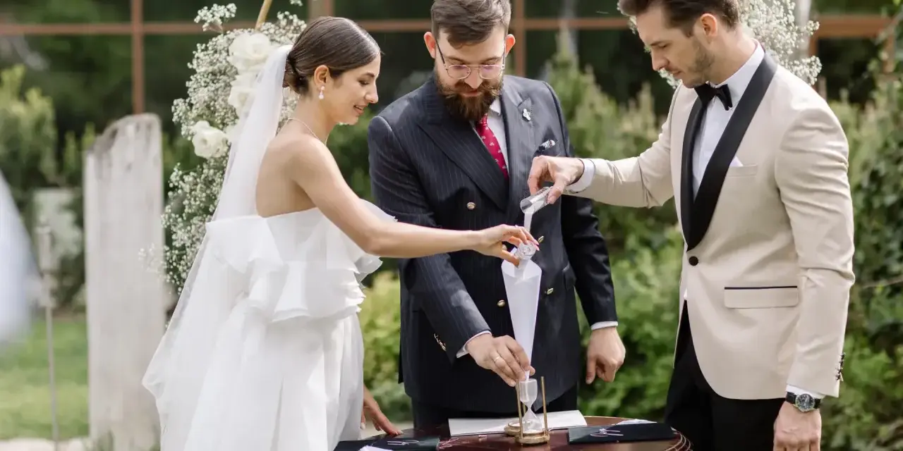 Para młoda podczas ceremonii, w tle łuk weselny. Zastanawiasz się nad wedding planner cena?