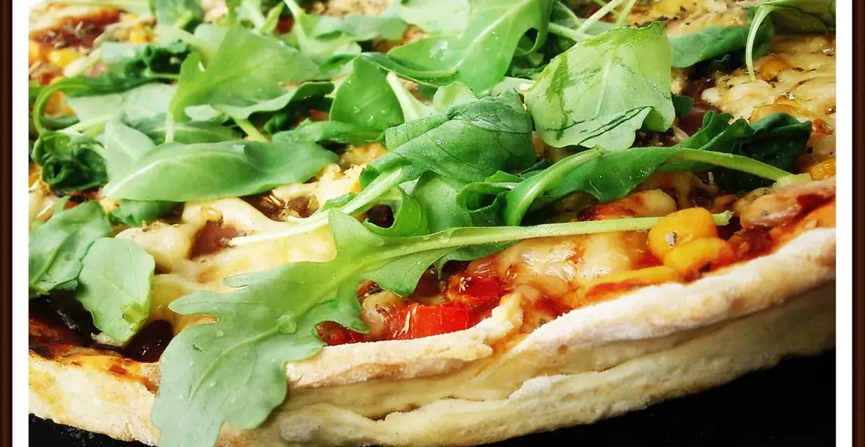 Pyszna pizza z rukolą, pomidorami i serem, pachnąca ziołami. Idealna na szybki obiad.
