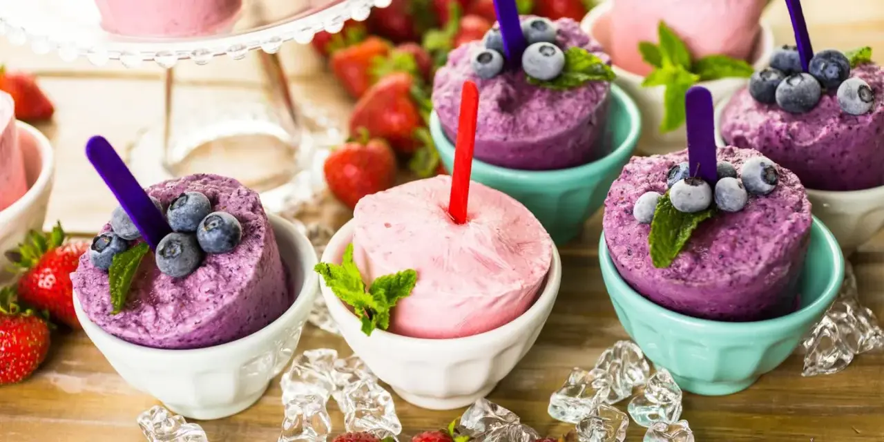 Erfrischendes Eis in Schalen, perfekt zum **Crème double selber machen**. Blaubeeren und Erdbeeren garnieren die bunten Leckereien.