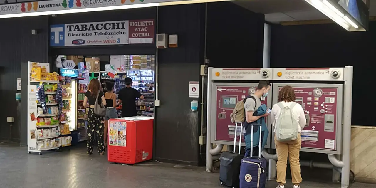 Na dworcu w Rzymie Ciampino ludzie kupują bilety i artykuły w sklepie.